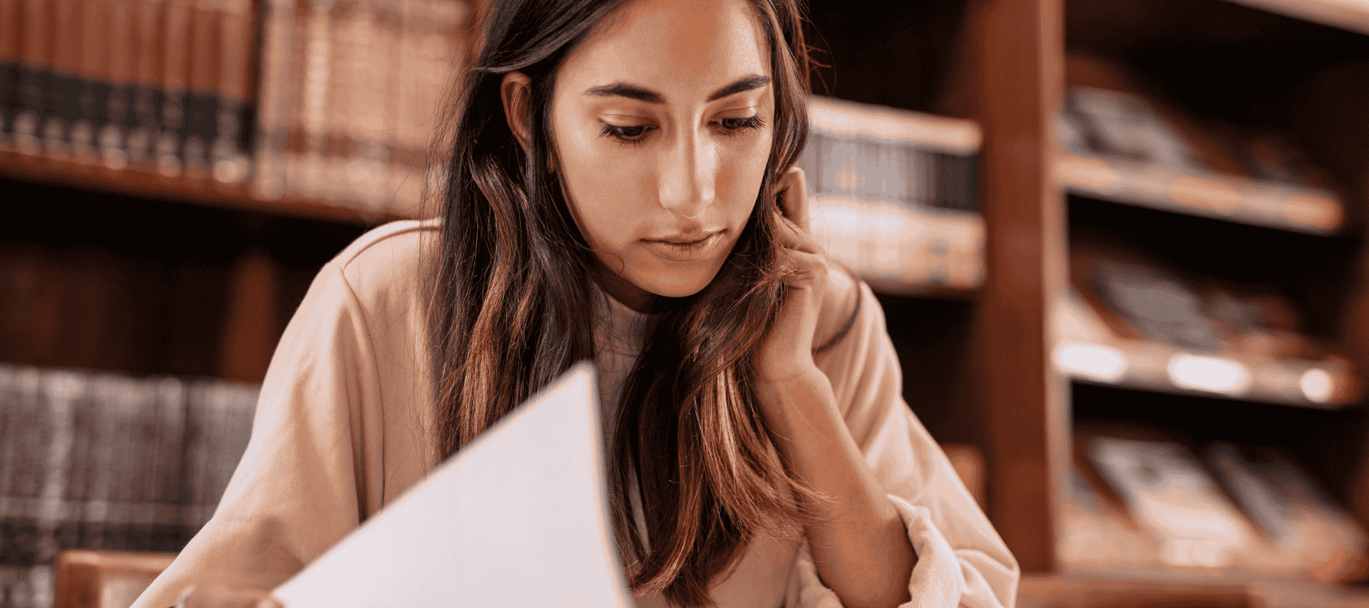 Teenage girl sits in a library studying
