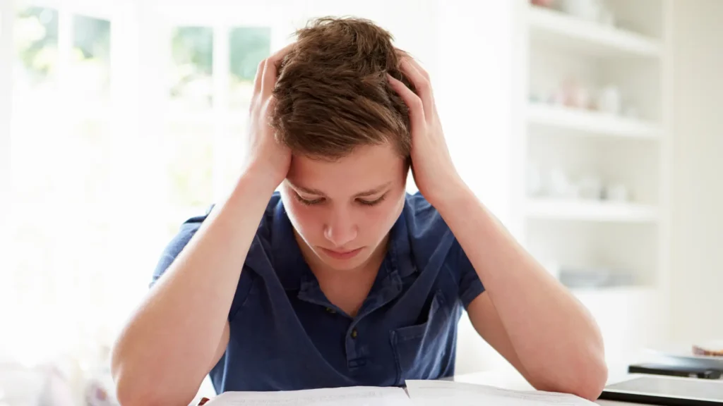 stressed teenager with head in hands after looking at A level results