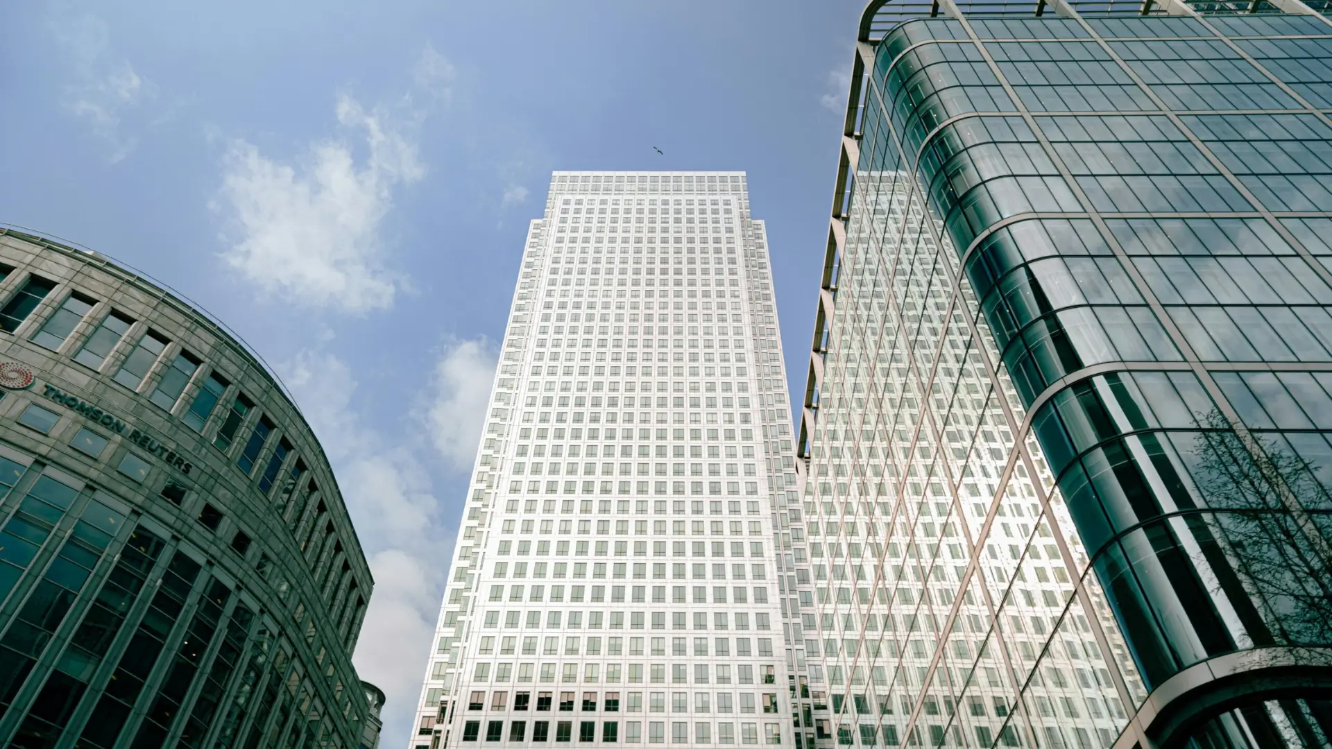 Upward view of modern glass office buildings in a financial district, symbolising global economics, trade, and business activity.