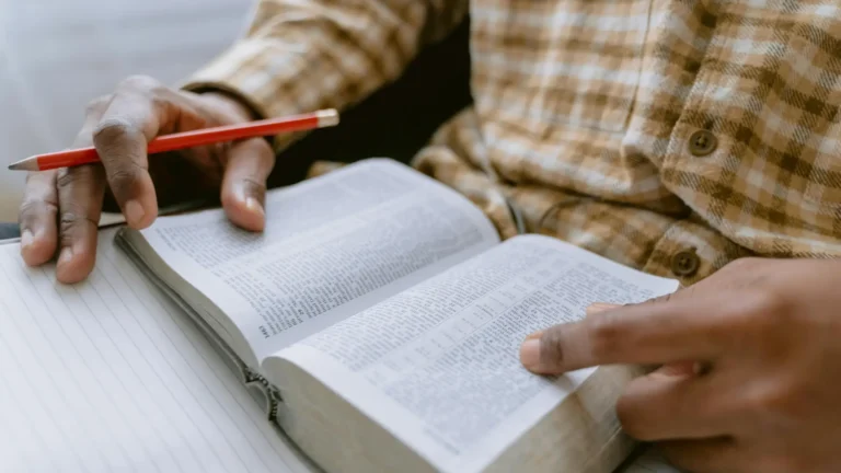 A person reading a text and making notes with a pencil, symbolising the academic study of religion, ethics, and philosophy.