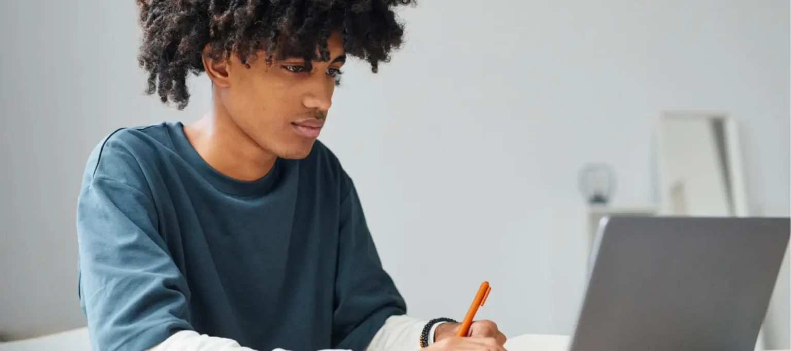 Boy studying his AS levels sat a desk using a lap top