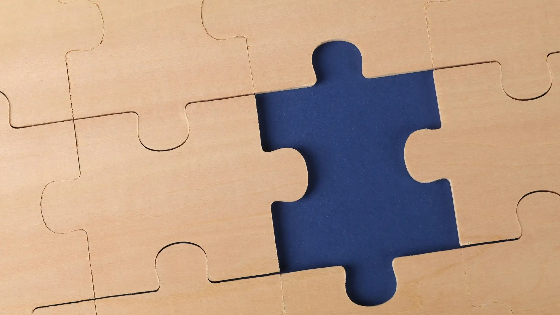 Close-up of wooden jigsaw puzzle pieces with one missing, symbolising the study of human thought and behaviour in A level Psychology.