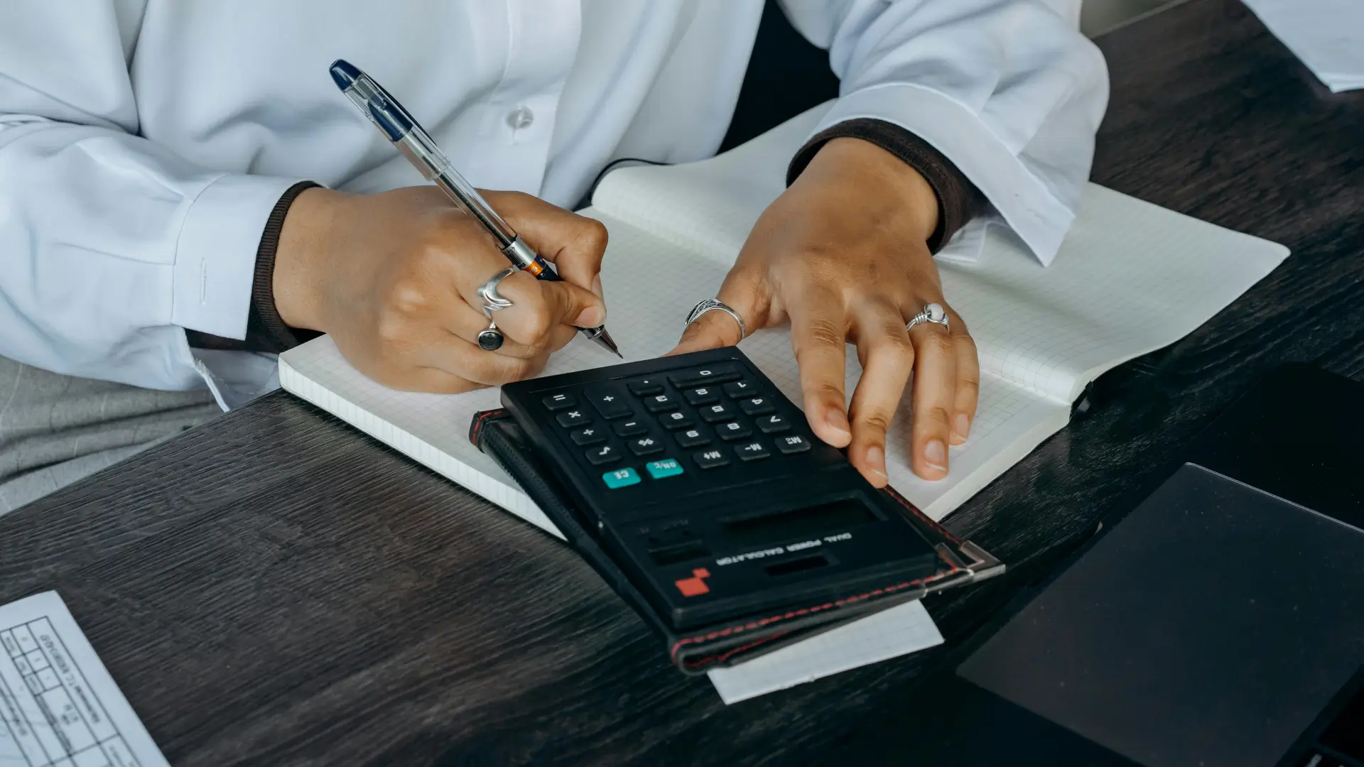 Close-up of a student using a calculator while writing in a squared notebook, representing advanced mathematical problem-solving.