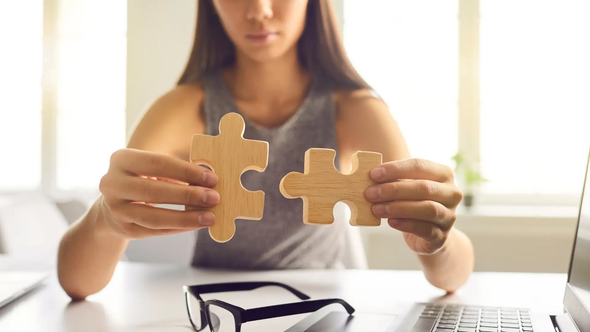 Two jigsaw pieces being held up over a desk
