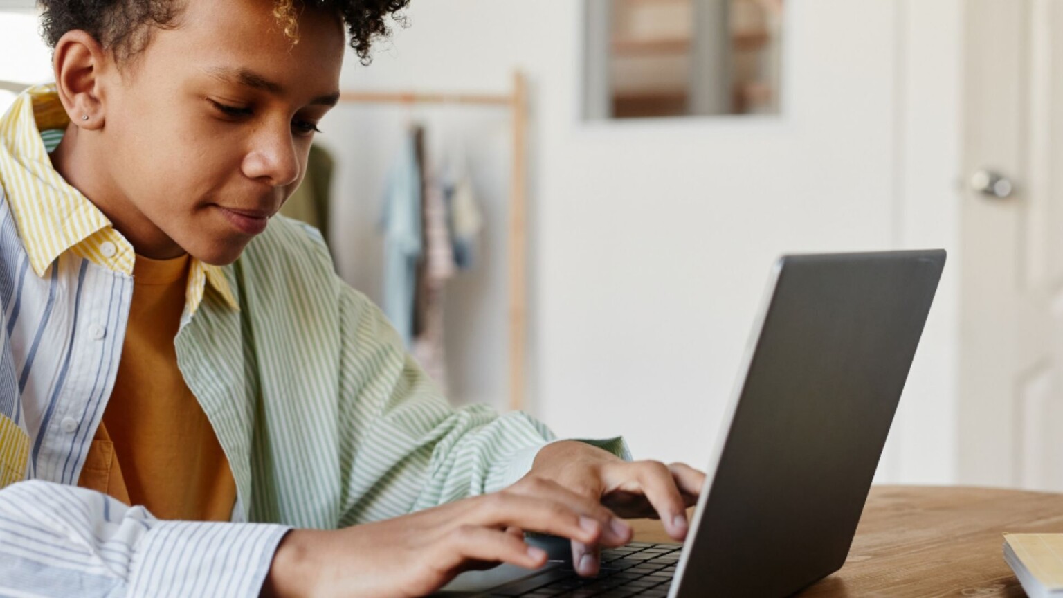 teenage boy sits at home using a laptop