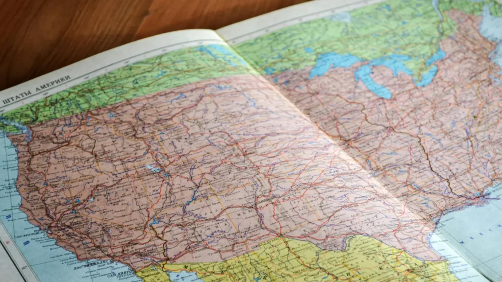 A detailed map of the United States with Russian labels, spread open on a wooden table—symbolising global awareness, spatial understanding, and geographical exploration.