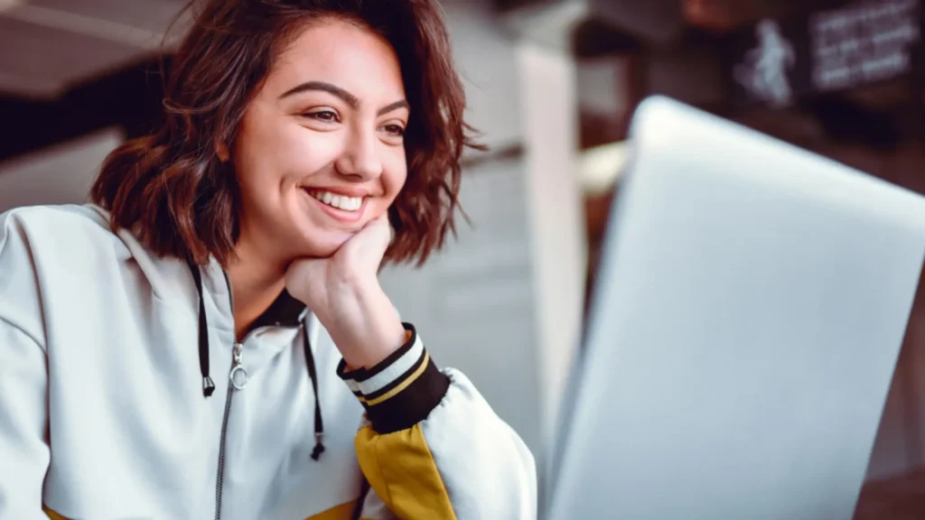 Happy female student looking at laptop