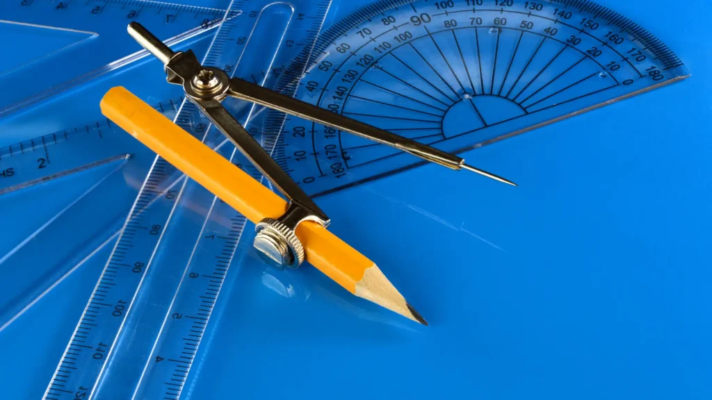 A set square, compass and protractor lay on a desk