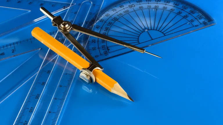 A set square, compass and protractor lay on a desk