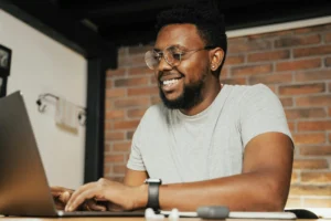 Smiling student working on a laptop, representing NEC’s inclusive and adaptive online learning approach.