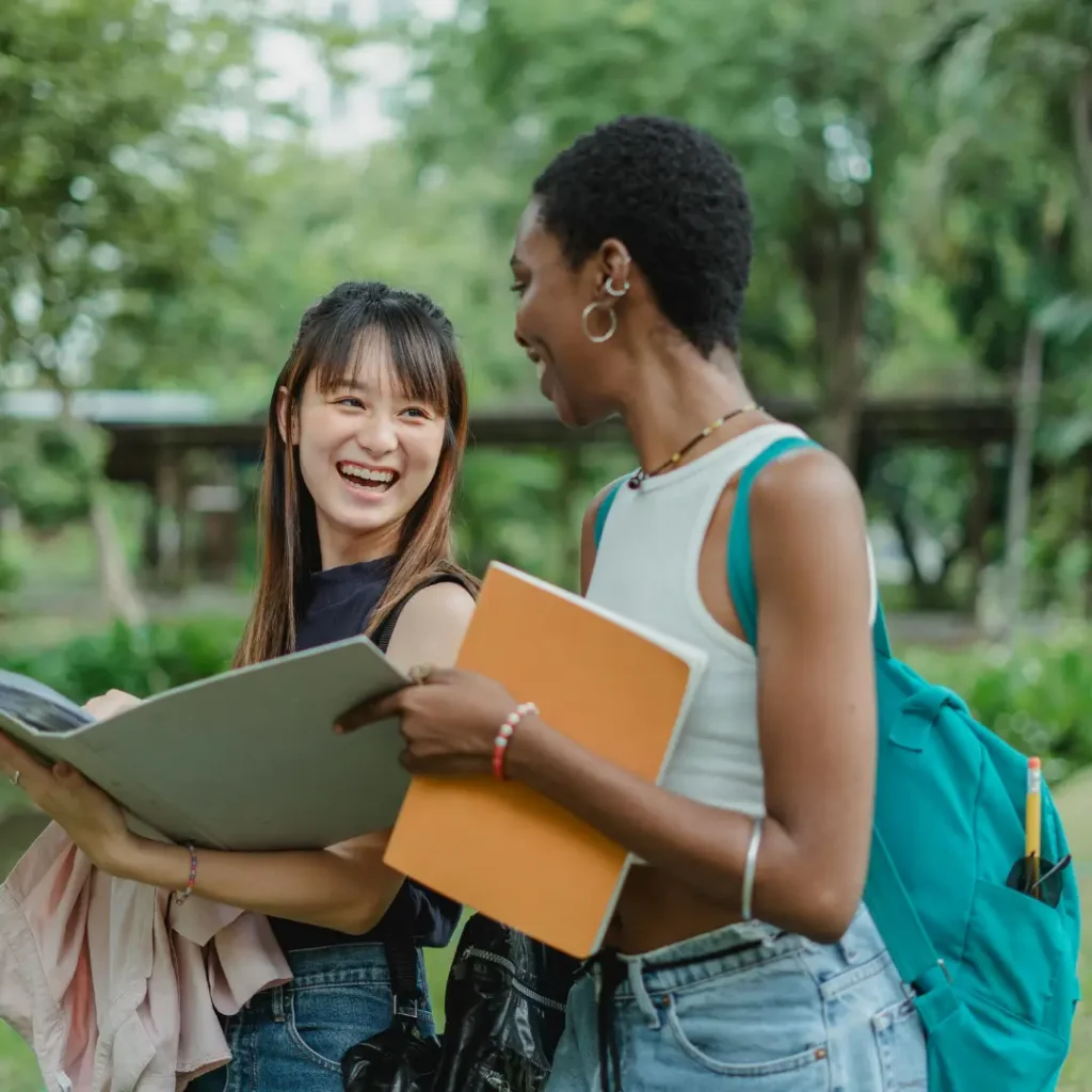 Two teenage girls with their study notes, smiling and laughing.