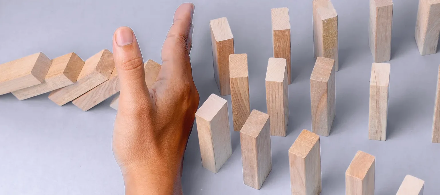 A hand putting a stop in a line of dominoes