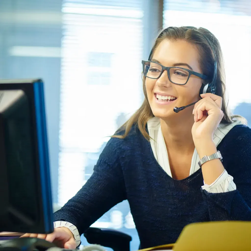 Talk to our course advice team about which GCSE courses to choose, female answering a call with her headset on in front of a PC.
