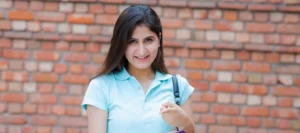 Smiling female student in a pale blue t-shirt points at the camera