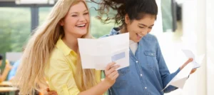 Two late teenaged girls with their exam results and big smiles on their faces