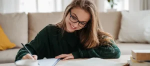 Smiling female student sits on the floor whilst studying