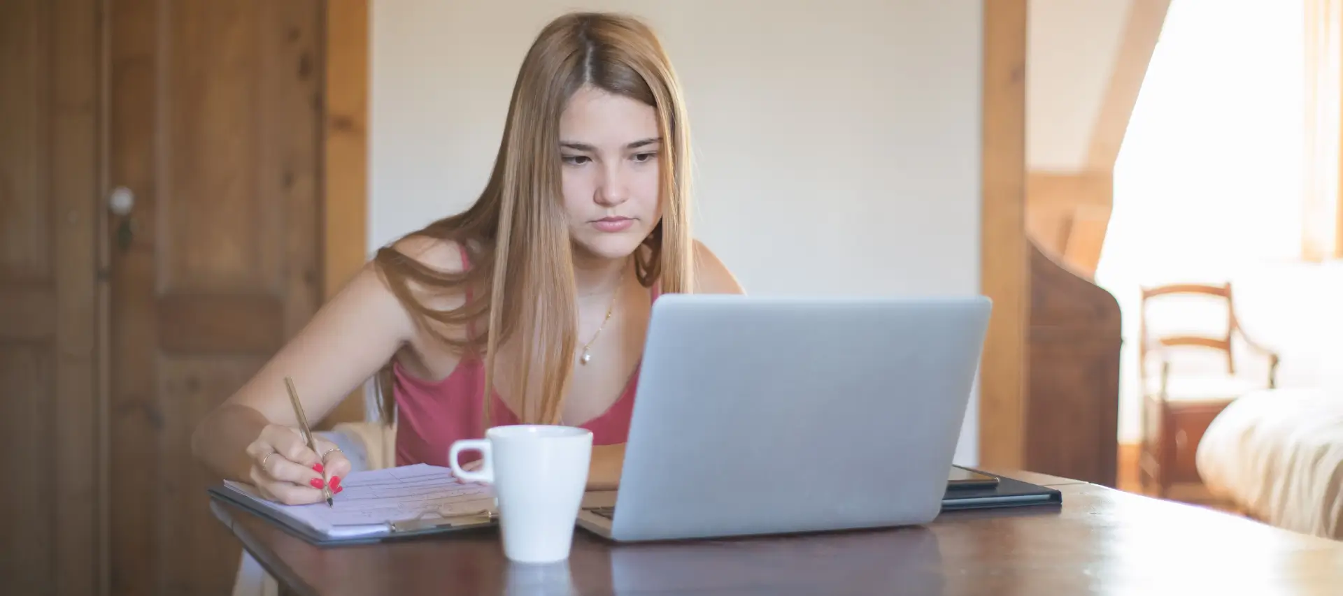 young female at desk on laptop retaking GCSEs online
