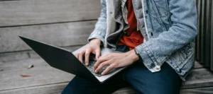 A student typing on a laptop while studying for NEC distance learning A levels.