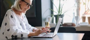 Woman in a spotty top sat at her laptop and smiling